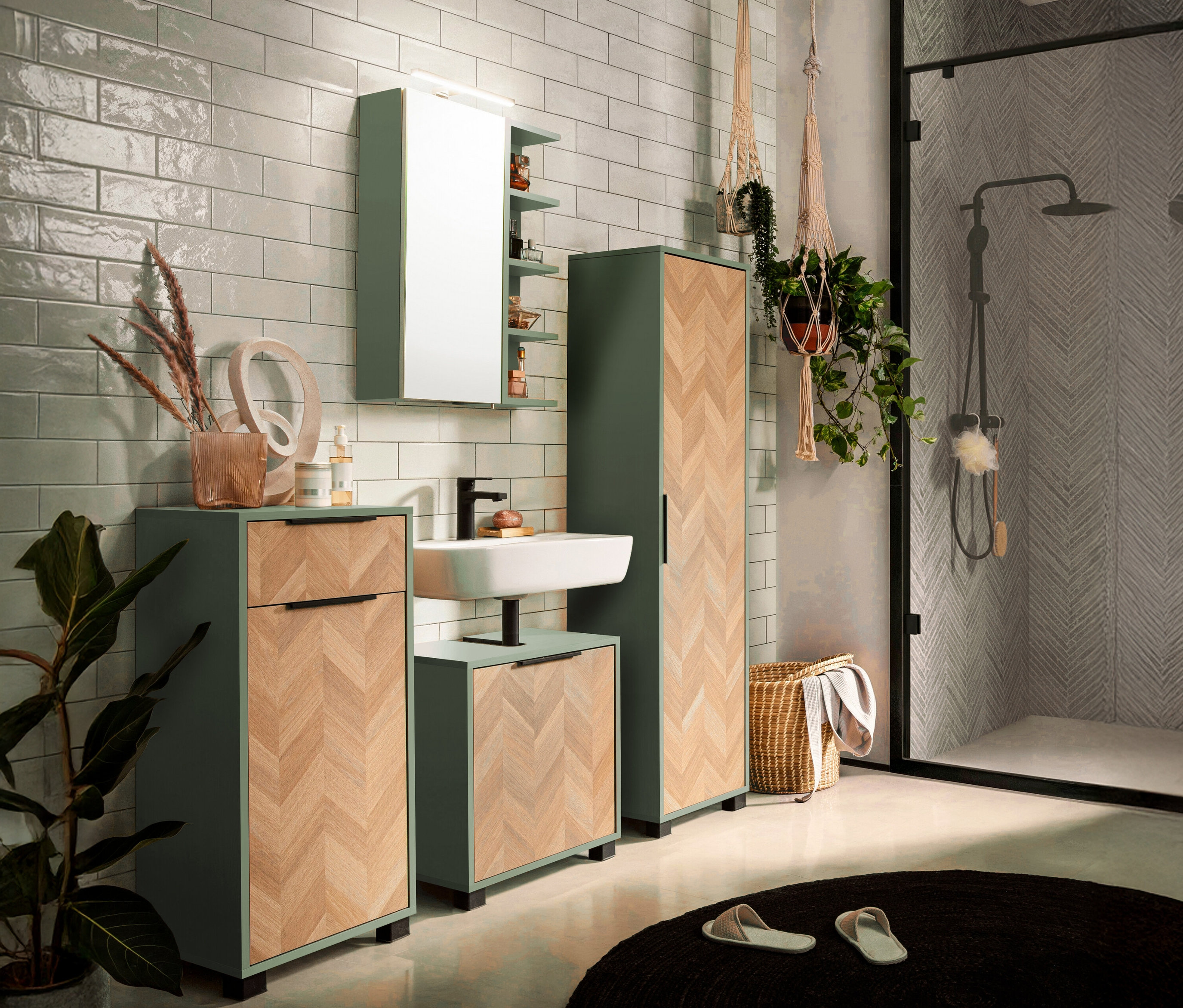Badezimmer mit Waschbeckenunterschrank, Hängeschrank, Spiegelschrank, Hochschrank in Grün und Holzoptik. Im Hintergrund eine Dusche.