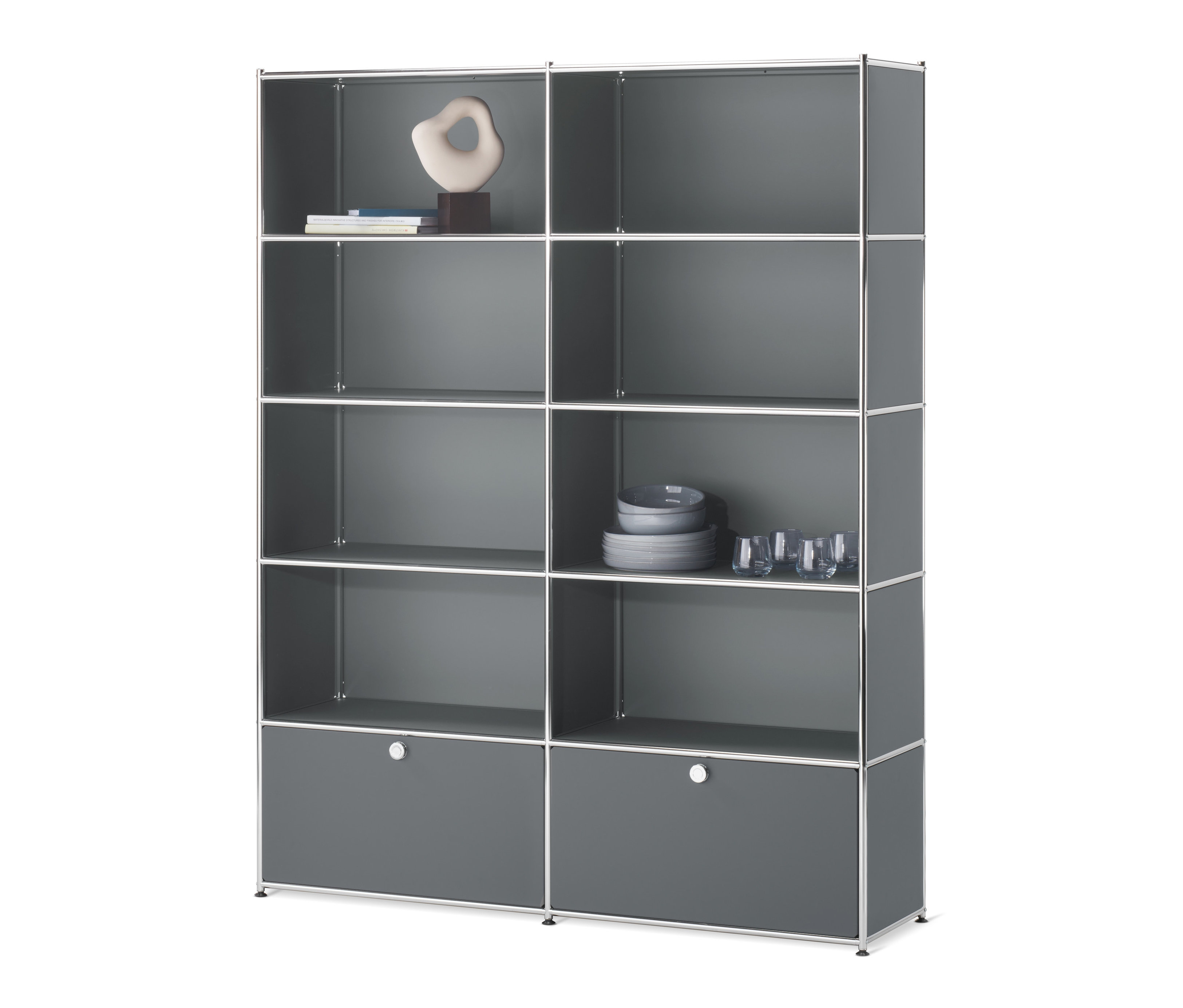 Graues Regal »CN3« mit 2 Klappen. In den oberen Regalfächern befinden sich Bücher, Dekoration und Geschirr.