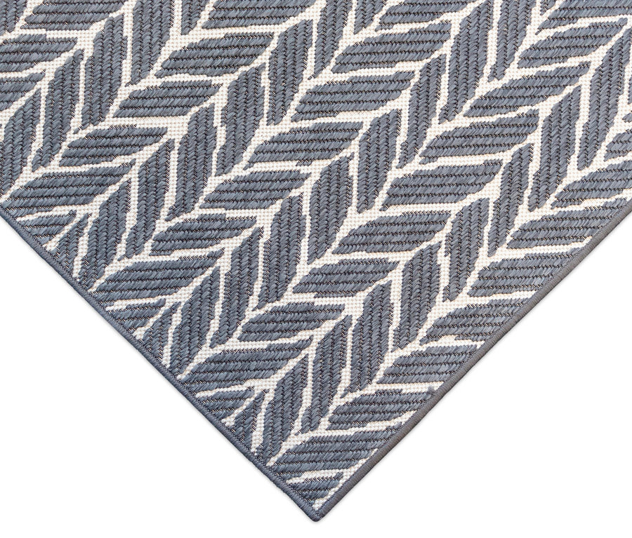Detailansicht eines grauen Outdoor-Wendeppichs »Knitted Joy« mit geometrischem Fischgrätenmuster.
