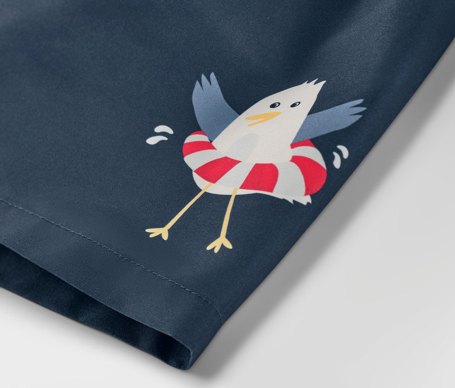 Detailaufnahme der Kinder-Boardshorts mit Maritim-Muster, bedruckt mit einer Möwe im Rettungsring.
