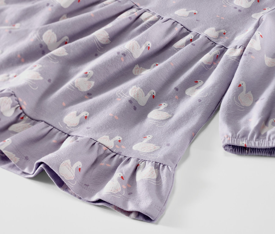 Detailaufnahme eines lila Baby-Jerseykleids mit Schwanenmuster.