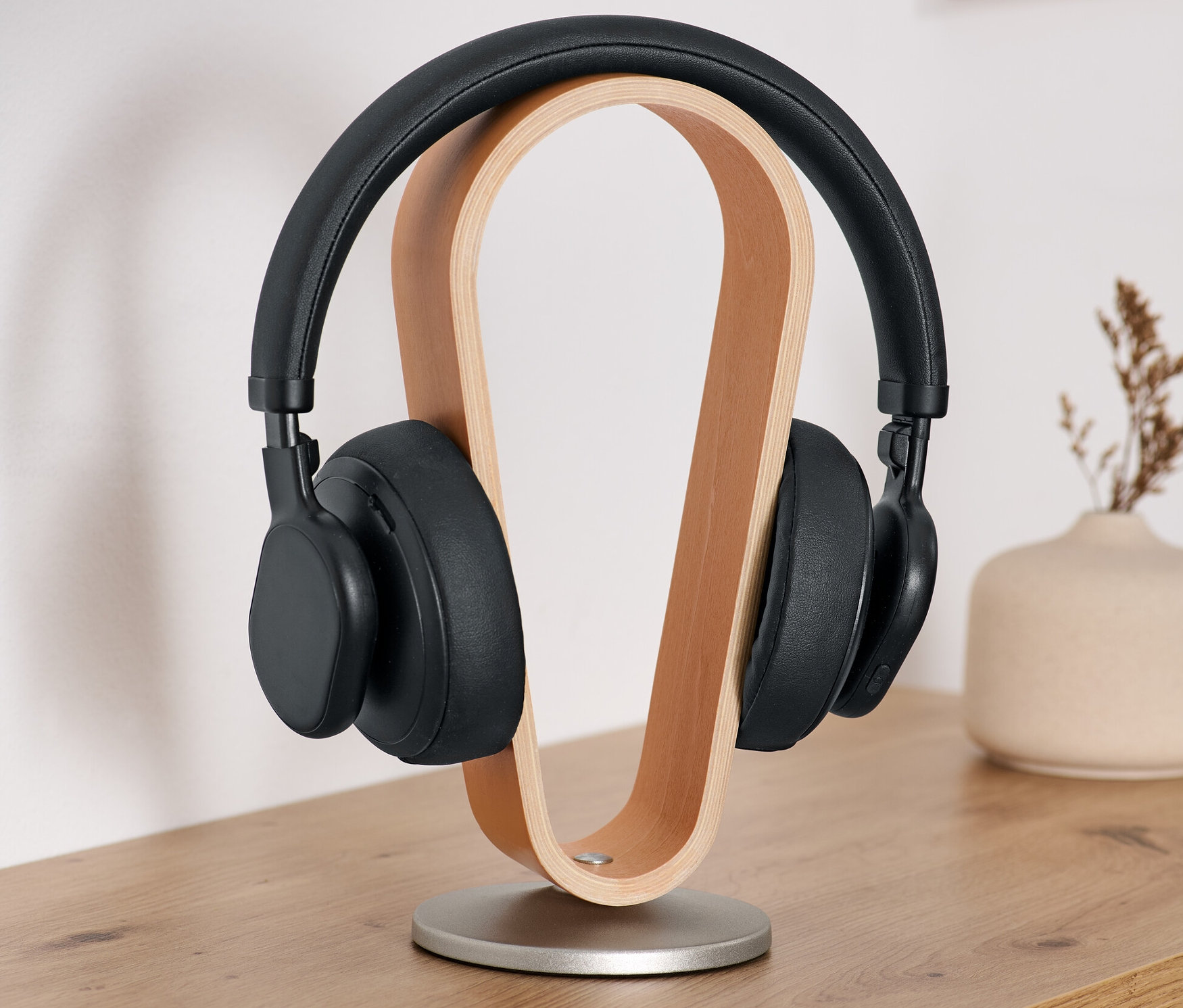 Schwarze Kopfhörer auf einem Kopfhörer-Ständer aus Holz.
