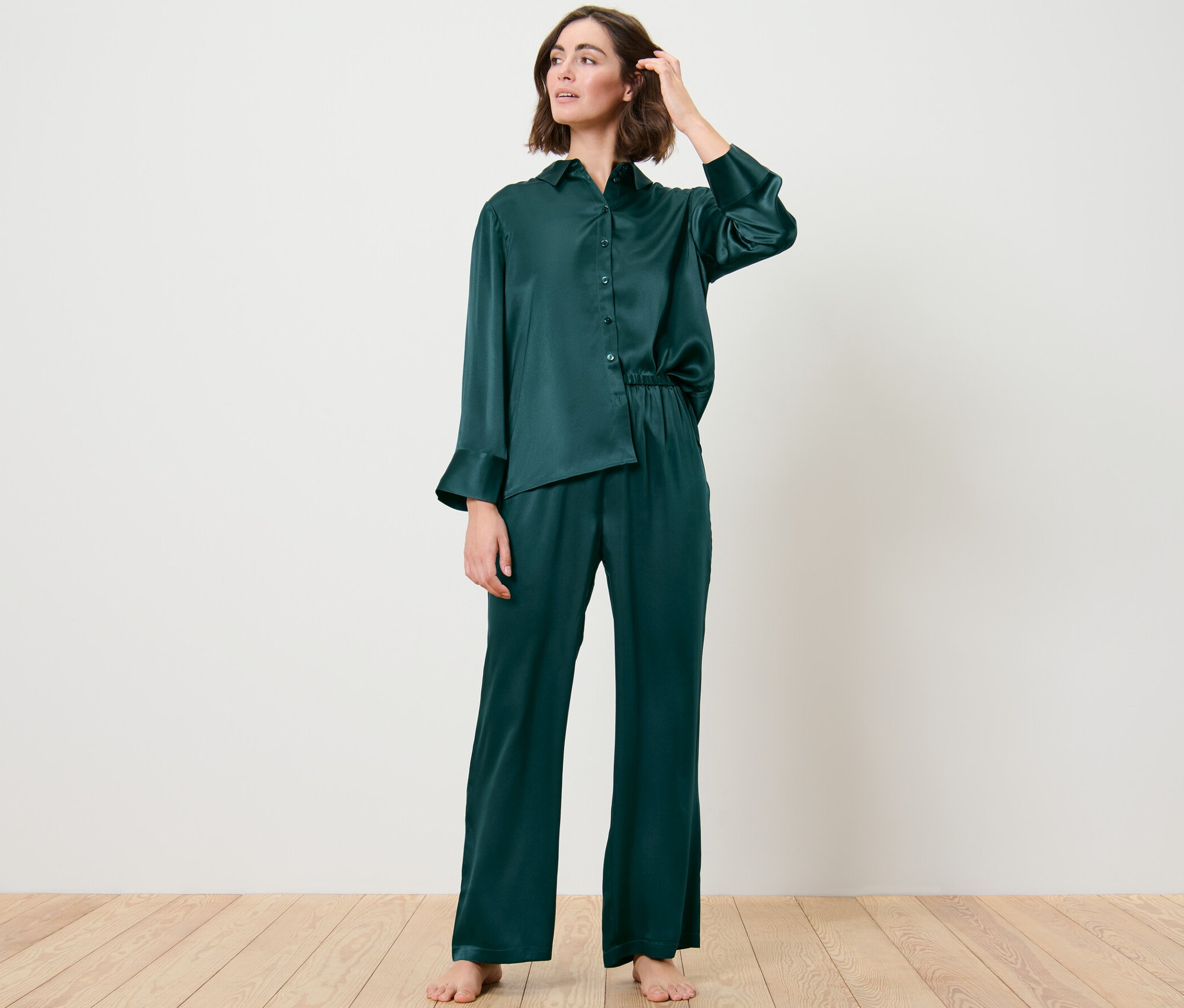 Frau trägt eine seidene Pyjamahose und posiert im Raum.
