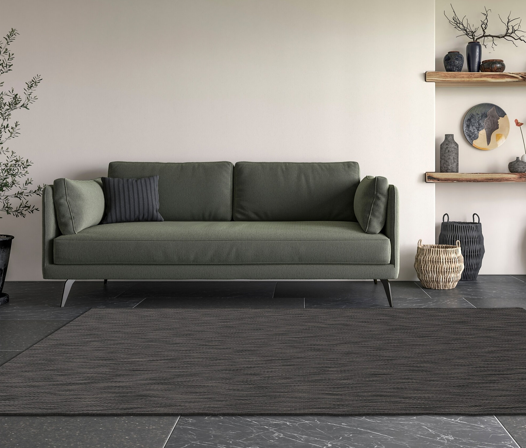 Ein dunkelgrauer Teppich »Eldorado« liegt vor einem grünen Sofa in einem Wohnzimmer.