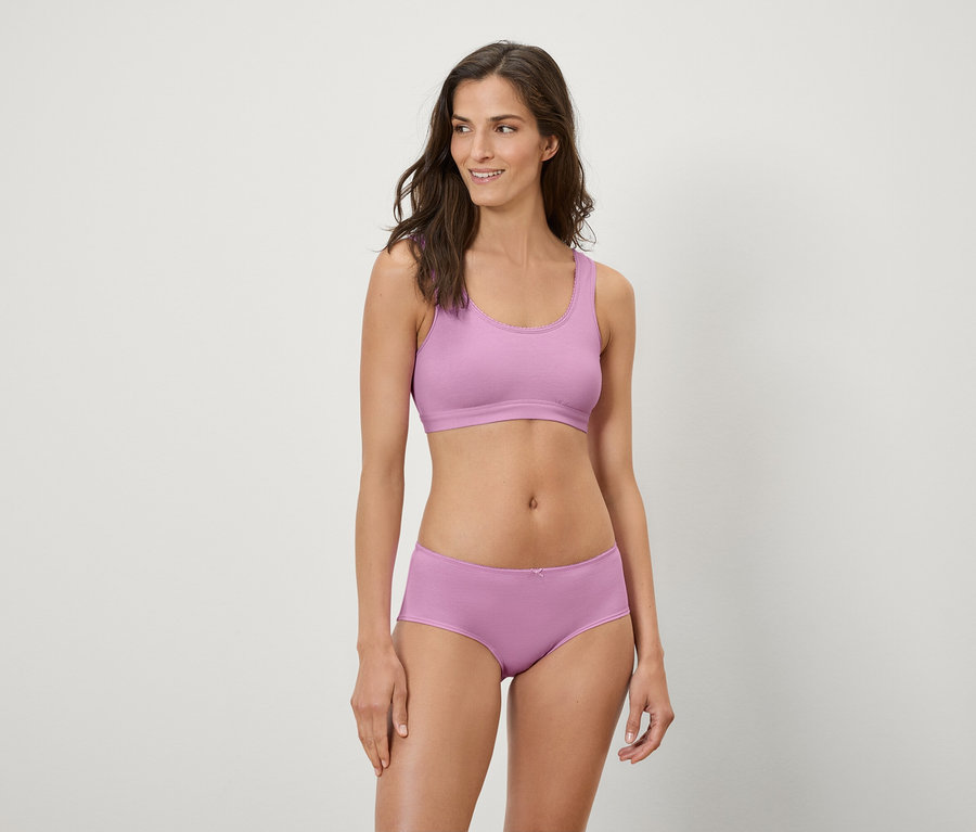 Frau posiert in lila Sport-BH und Boxershorts.