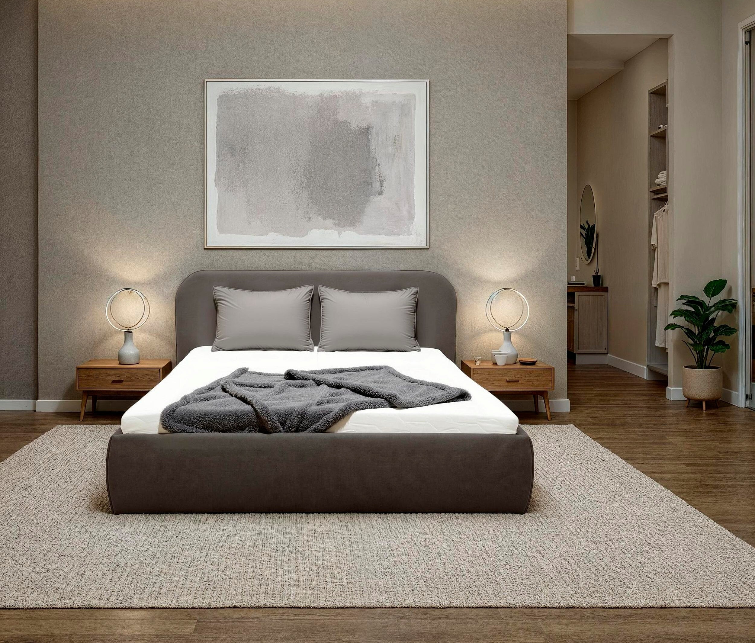 Schlafzimmer mit einem grauen Bett, grauen Kissen und einer grauen Decke auf einem weißen Bettlaken. Über dem Bett hängt ein Bild.