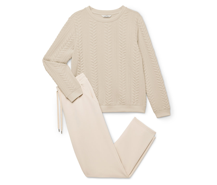 Beiger Hausanzug, bestehend aus einem Pullover mit Zopfmuster und einer Hose mit Kordelzug.