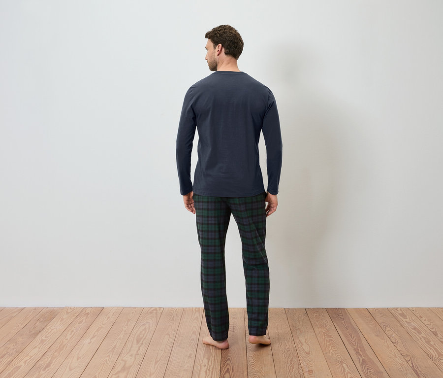 Mann von hinten trägt ein dunkelblaues Schlafshirt und eine karierte Schlafanzughose.