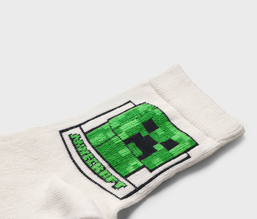 Nahaufnahme einer weißen Socke mit einem grünen Minecraft-Creeper-Motiv.