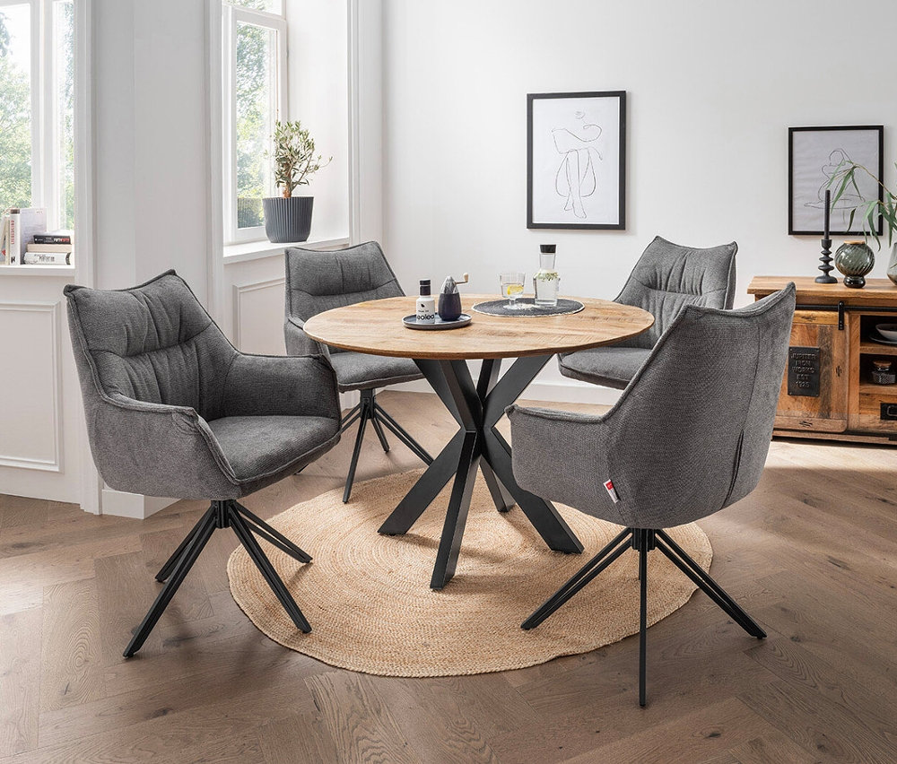 Vier drehbare, dunkelgraue DeVries Diningsessel »Ginosa« stehen um einen runden Holztisch auf einem Teppich.