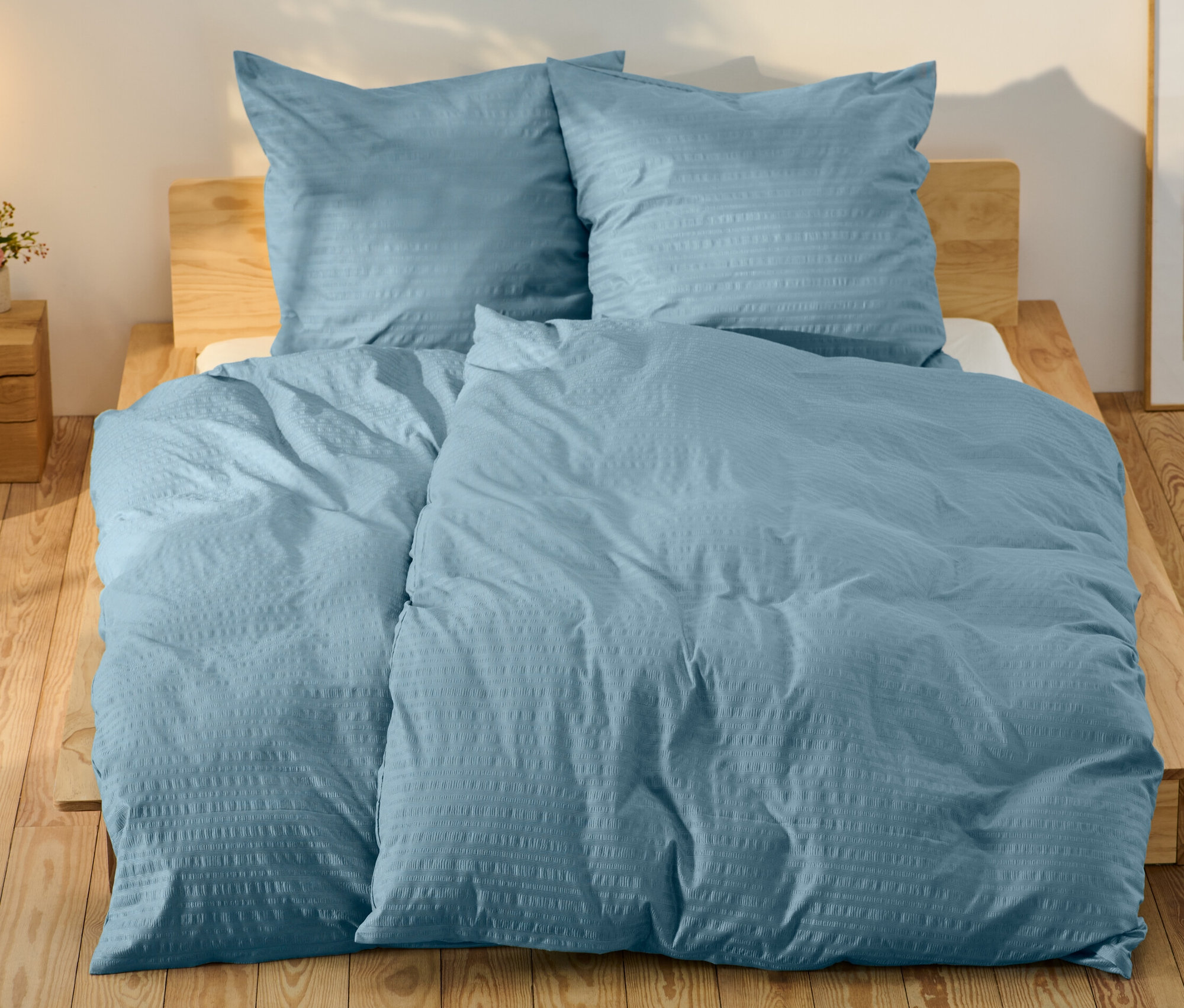 Blaue Seersucker-Bettwäsche in Normalgröße und Übergröße auf einem Bett.
