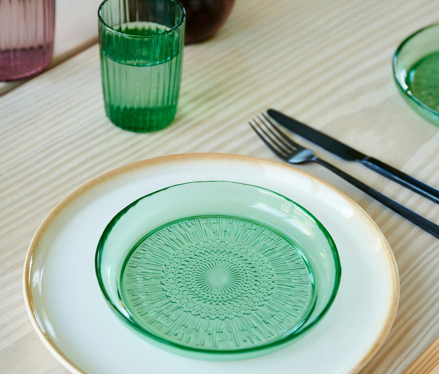 Auf einem Tisch stehen zwei grüne Glasteller "Kusintha" von Bitz, 18 cm.