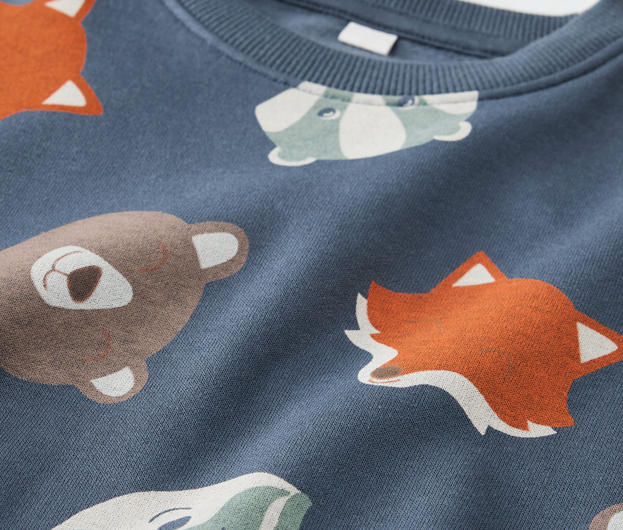 Detailansicht eines blauen Kinder-Sweatshirts mit Tiermotiven.