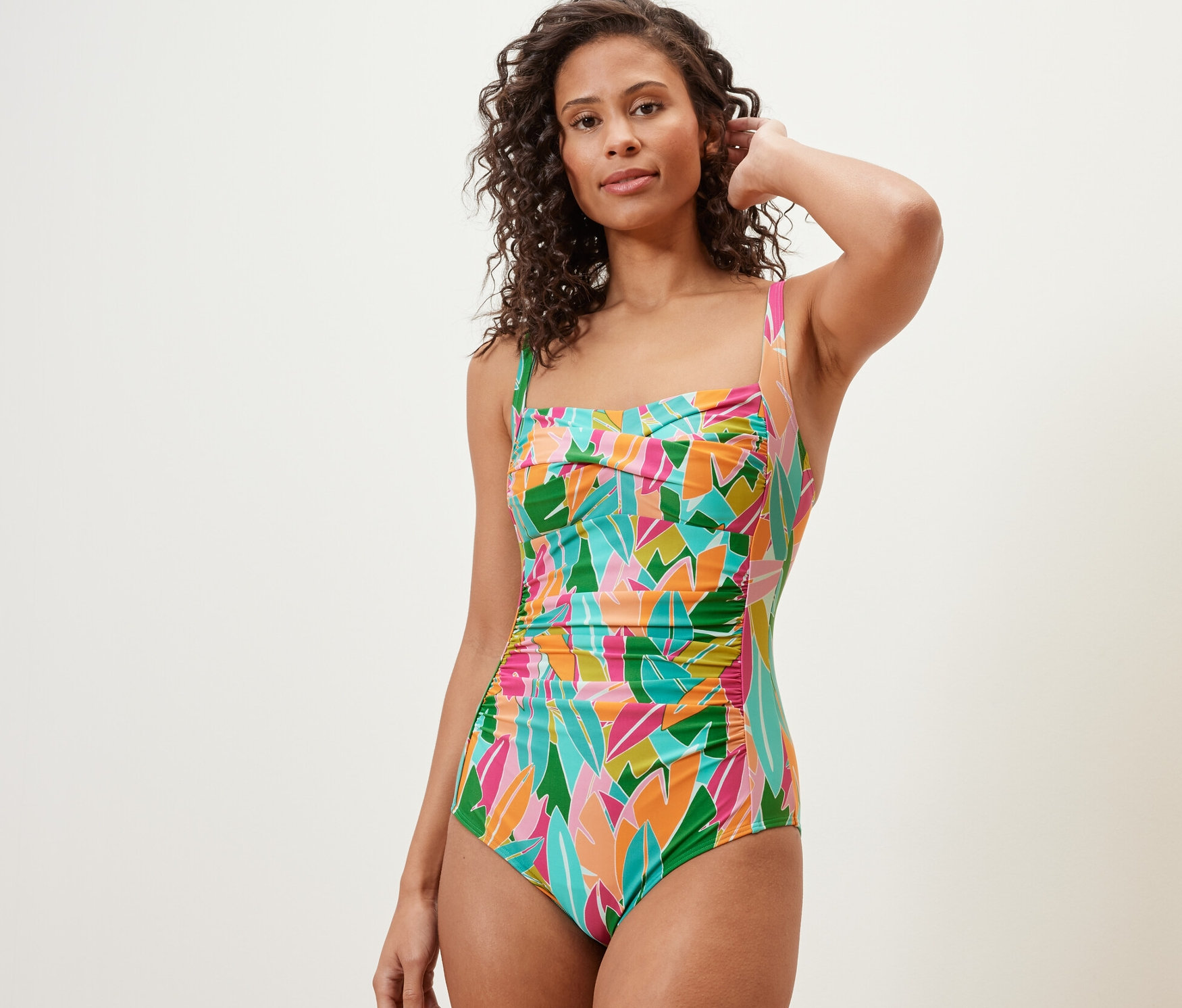 Frau posiert in einem mehrfarbigen, figurformenden Badeanzug.