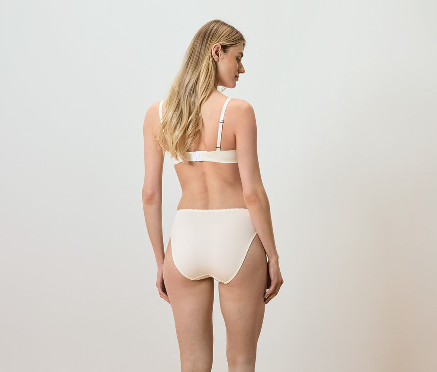 Rückansicht einer Frau mit blonden Haaren, die einen beigen BH und Slip trägt.