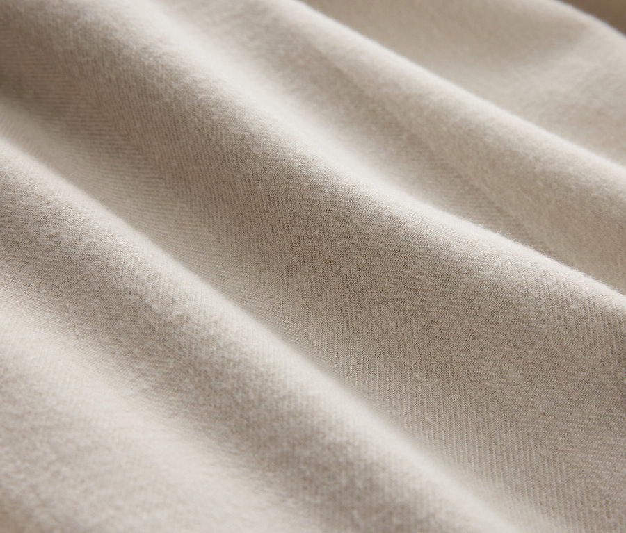 Detailaufnahme eines cremefarbenen Stoffes mit sanften Falten.