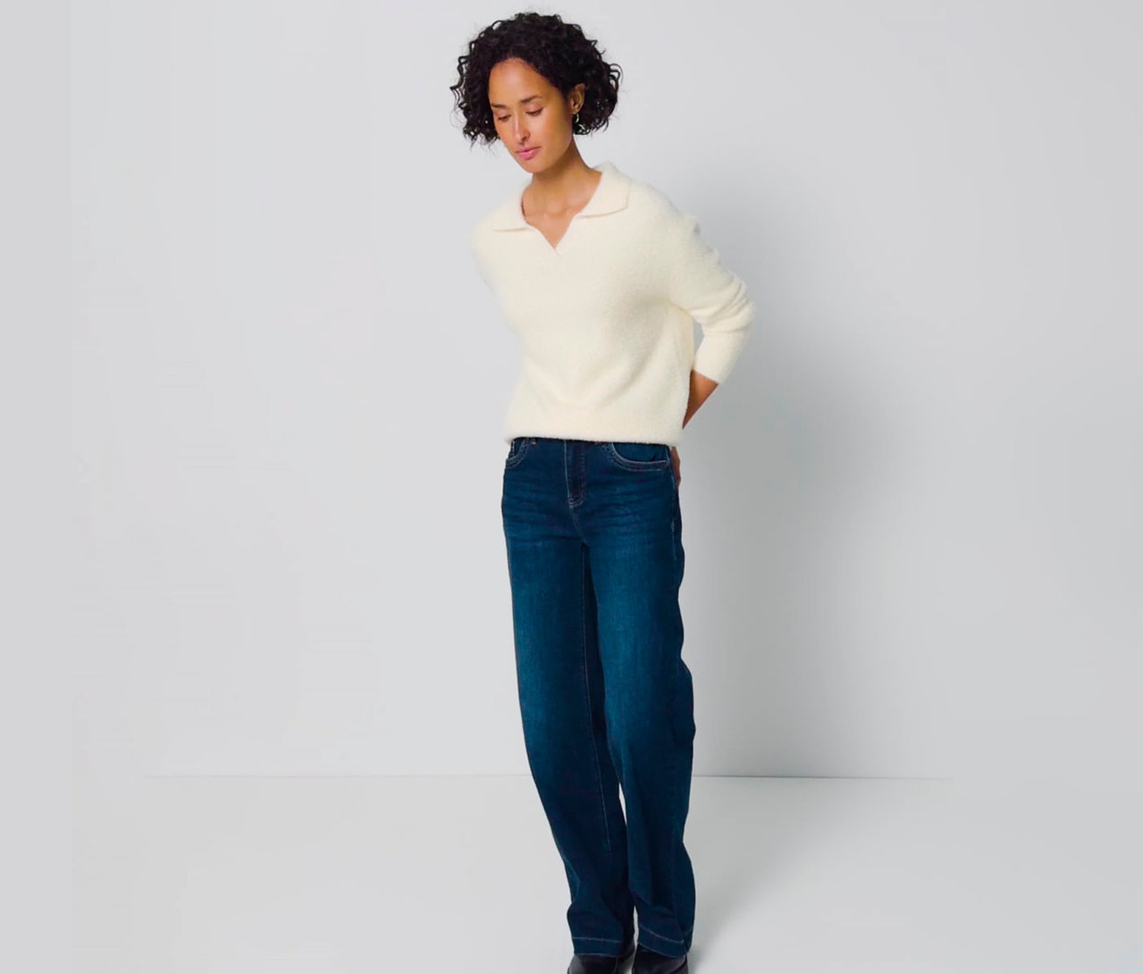 Frau trägt einen cremefarbenen Street One Strickpullover mit Polokragen und blaue Jeans.