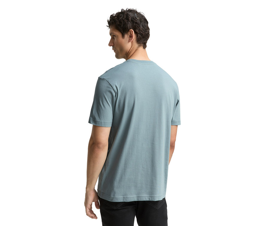 Mann von hinten in Grey Mint Tom Tailor T-Shirt mit Logo und schwarzen Jeans.