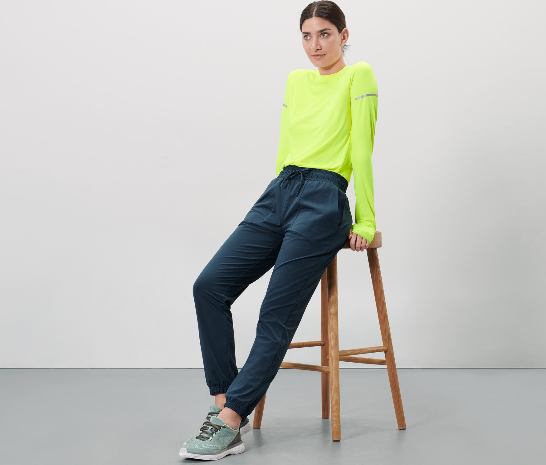 Frau sitzt auf einem Hocker und trägt eine Thermohose.