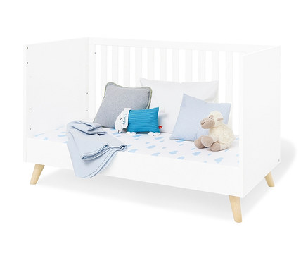 Weißes Pinolino Babybett »Move« mit blauen und weißen Kissen und einem Stoffschaf.