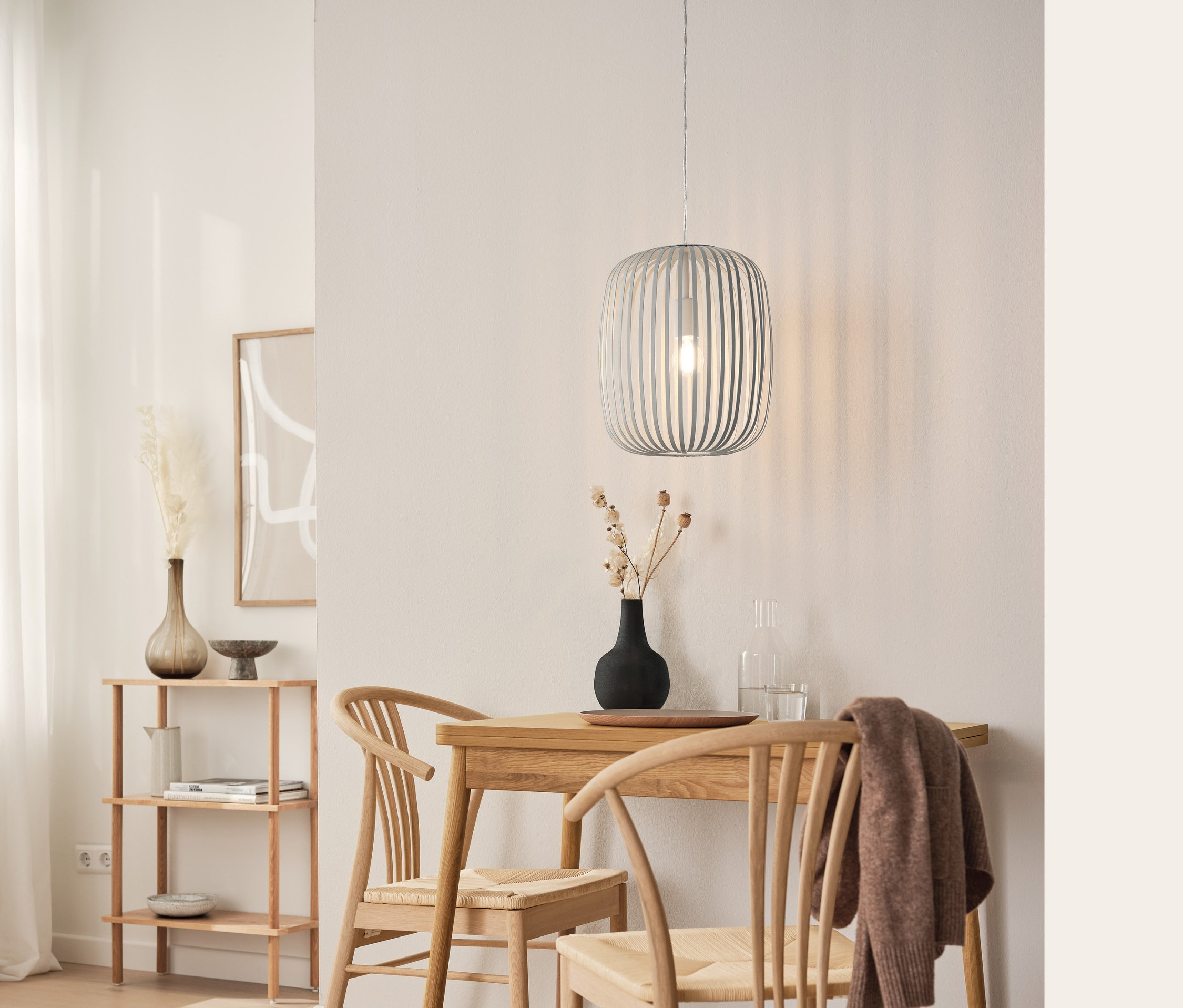 Essbereich mit erweiterbarem Esstisch, Pendelleuchte aus Metall, Esszimmerstuhl aus Eichenholz und Standregal.