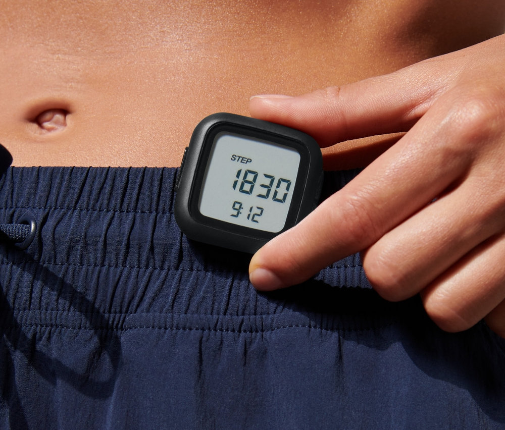 Frau hält Schrittzähler in der Hand.