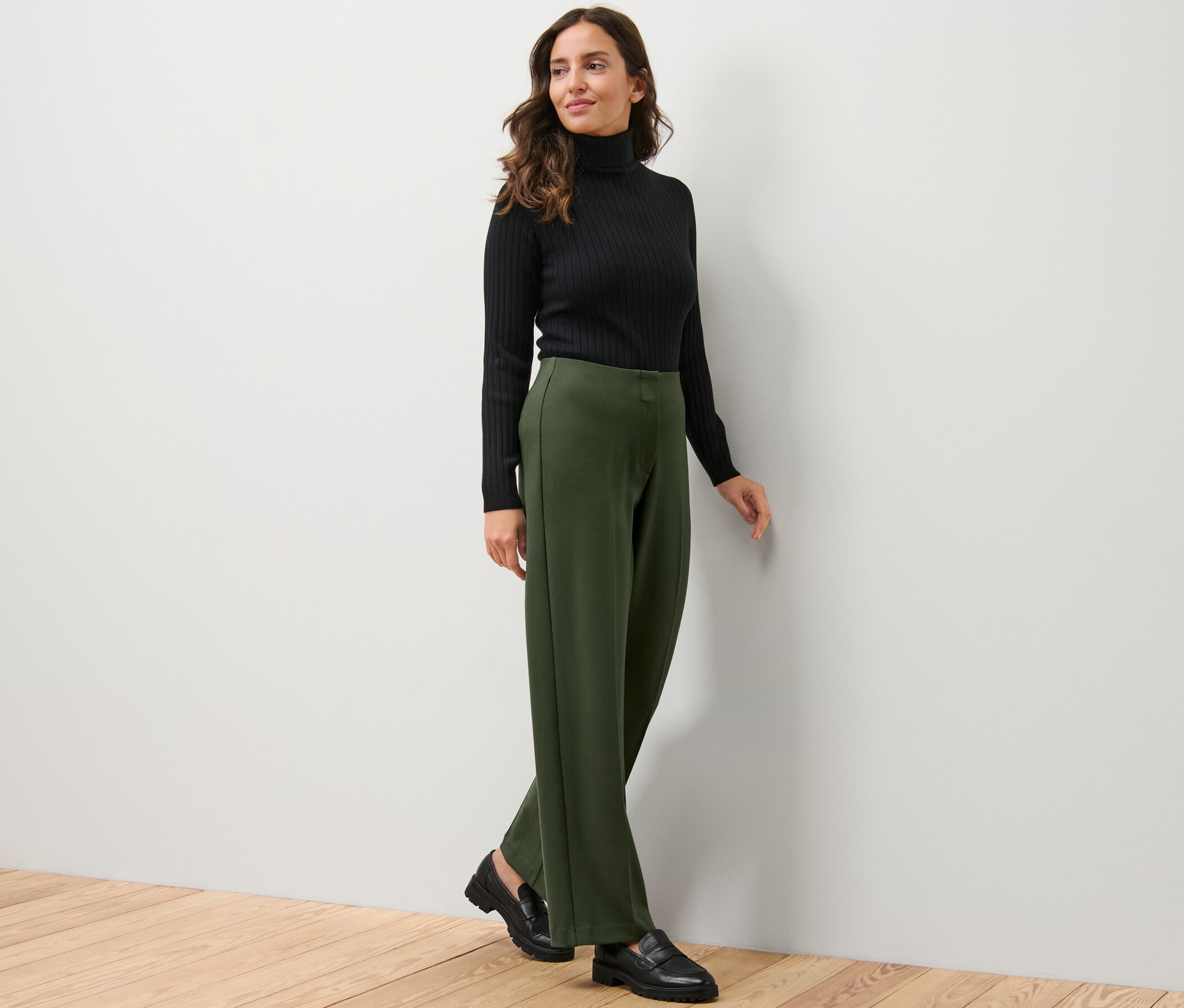 Frau trägt schwarzen Rollkragenpullover und Jerseyhose.