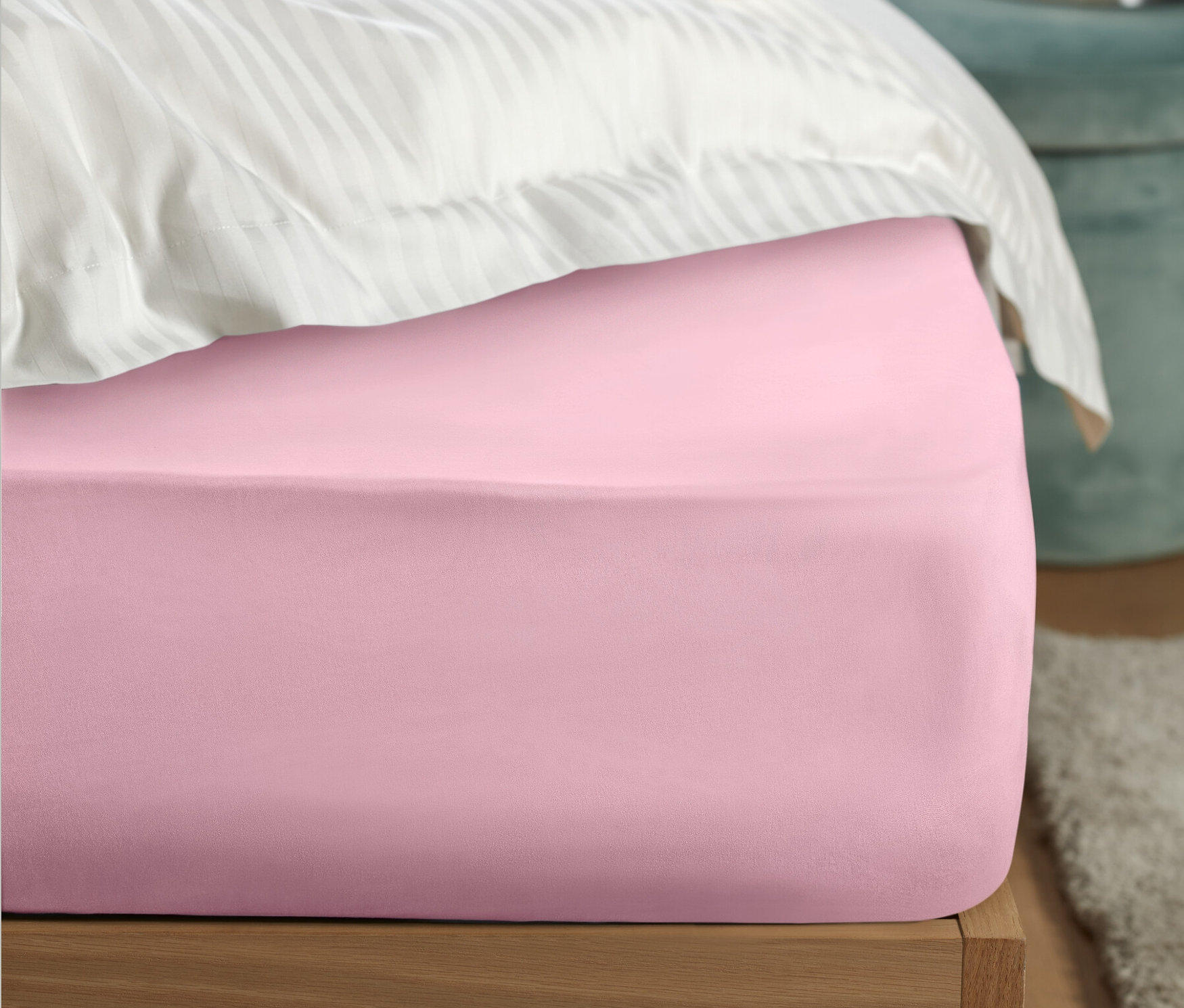 Detailaufnahme eines rosa Perkal-Spannbettlakens auf einem Bett.