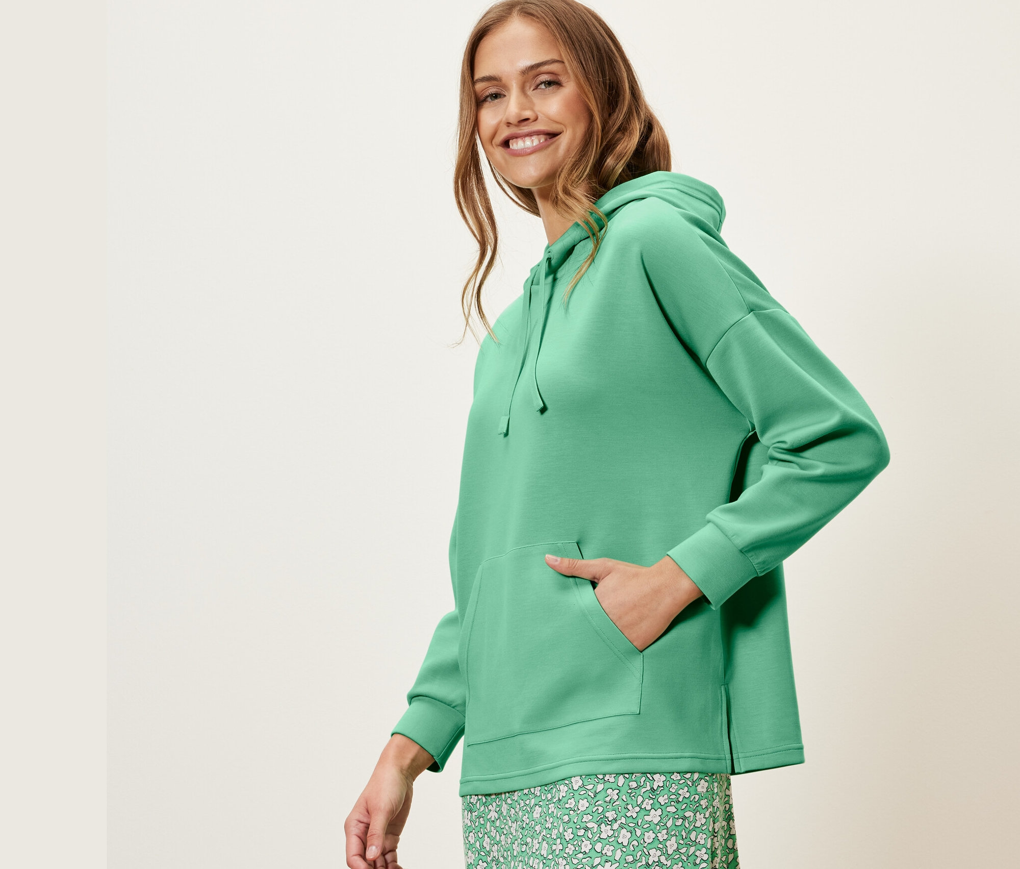 Frau posiert in grünem Hoodie aus Modal-Mix und grünem Blumenrock.