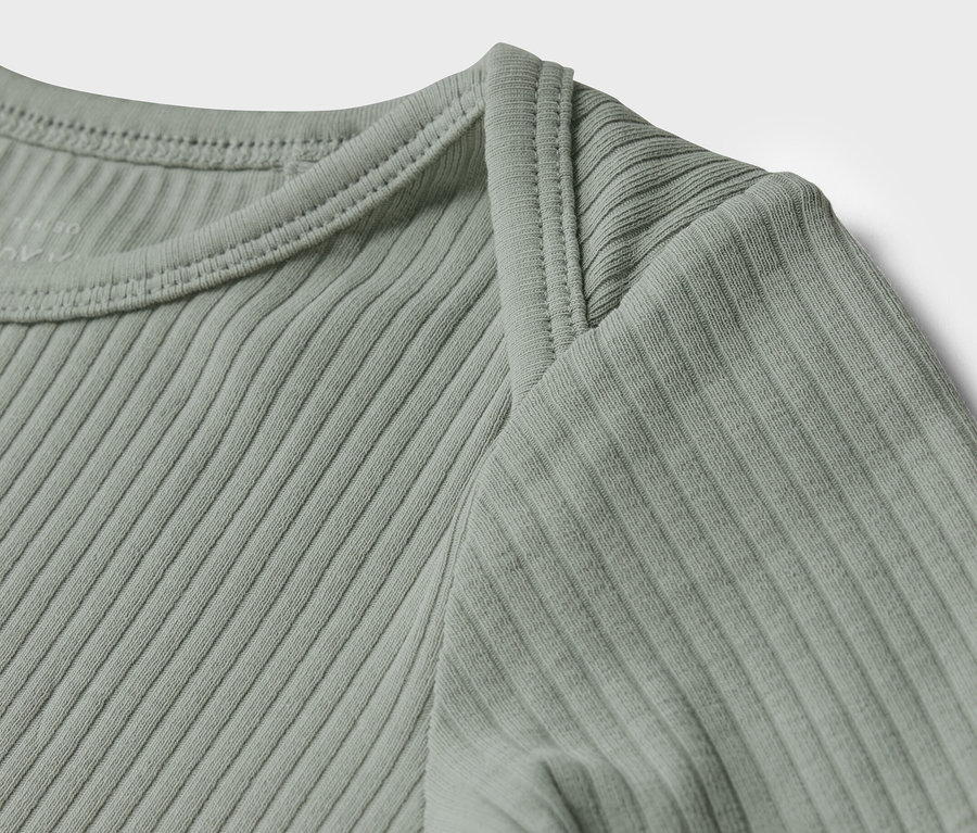 Detailansicht eines hellgrünen Baby-Langarmshirts mit Rippstruktur.