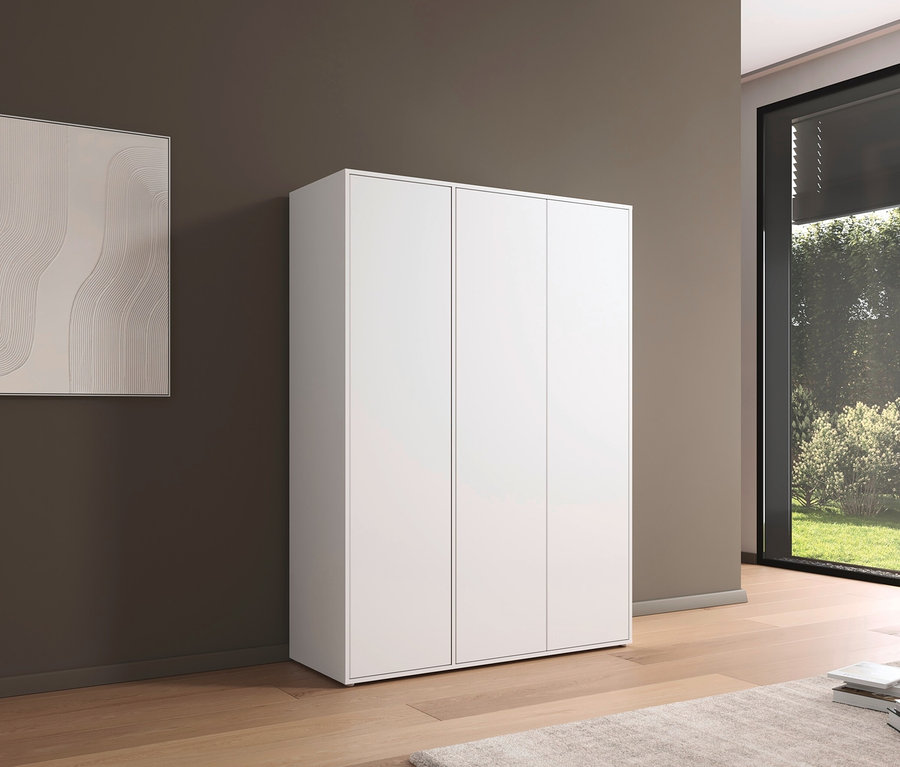 Weißer, dreitüriger rauch Kleiderschrank Nabilia steht auf Holzboden neben einer braunen Wand.