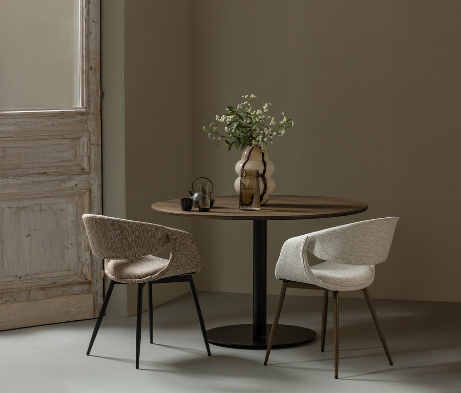 Zwei kupfer-naturfarbene WOOOD Esszimmerstühle »Yossi« mit Metallfuß stehen an einem runden Holztisch mit Blumenvase und Gläsern.