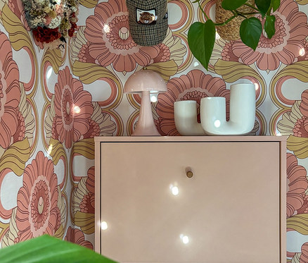 Aprikotfarbener Schuhschrank »Bjarne« mit drei Klappen vor gemusterter Wand.