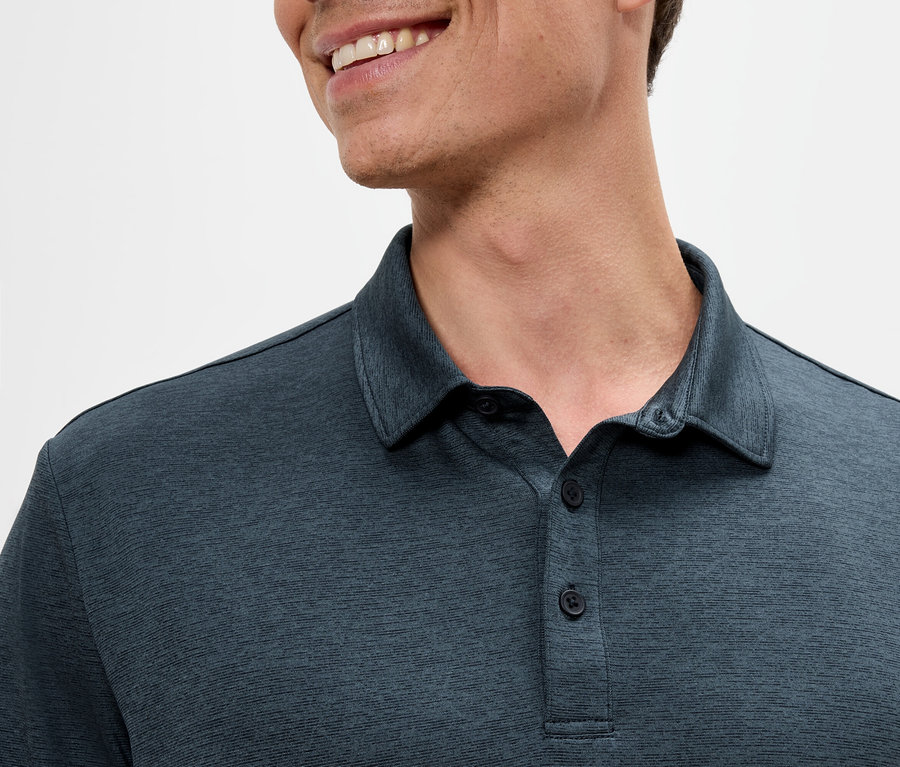 Nahaufnahme eines Mannes, der ein dunkelblaues Poloshirt trägt und lächelt.