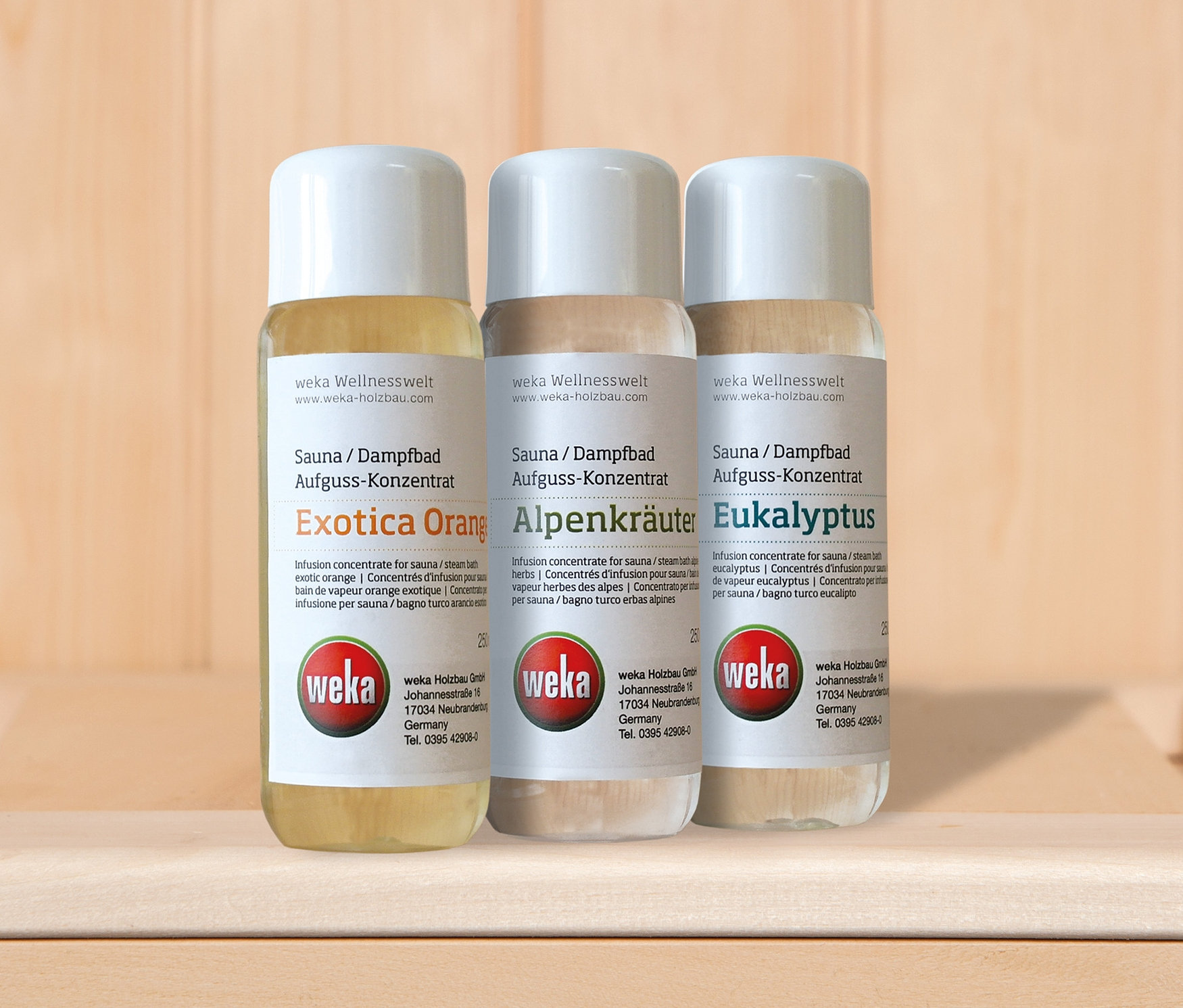 Drei Flaschen Weka Sauna-Premium-Zubehör-Set Duftöle stehen auf einem Holzregal.