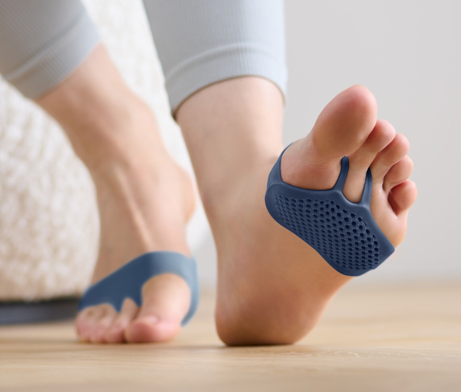 Füße mit blauen 2 Ballenpolstern auf Holzboden.