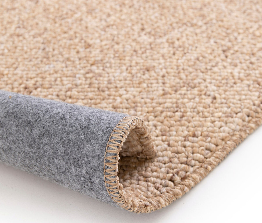 Detailansicht eines beigen Sisalteppichs »Lino«, der auf einem weißen Hintergrund aufgerollt ist.