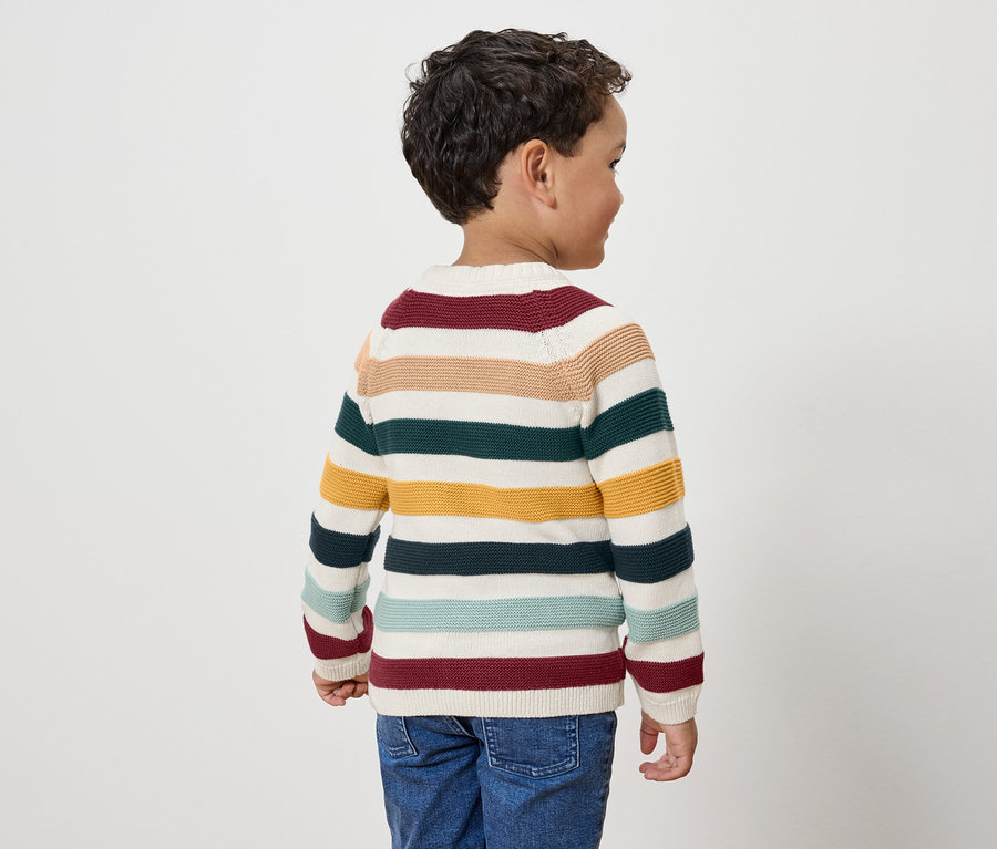 Junge mit gestreiftem Pullover, der mit dem Rücken zur Kamera steht.