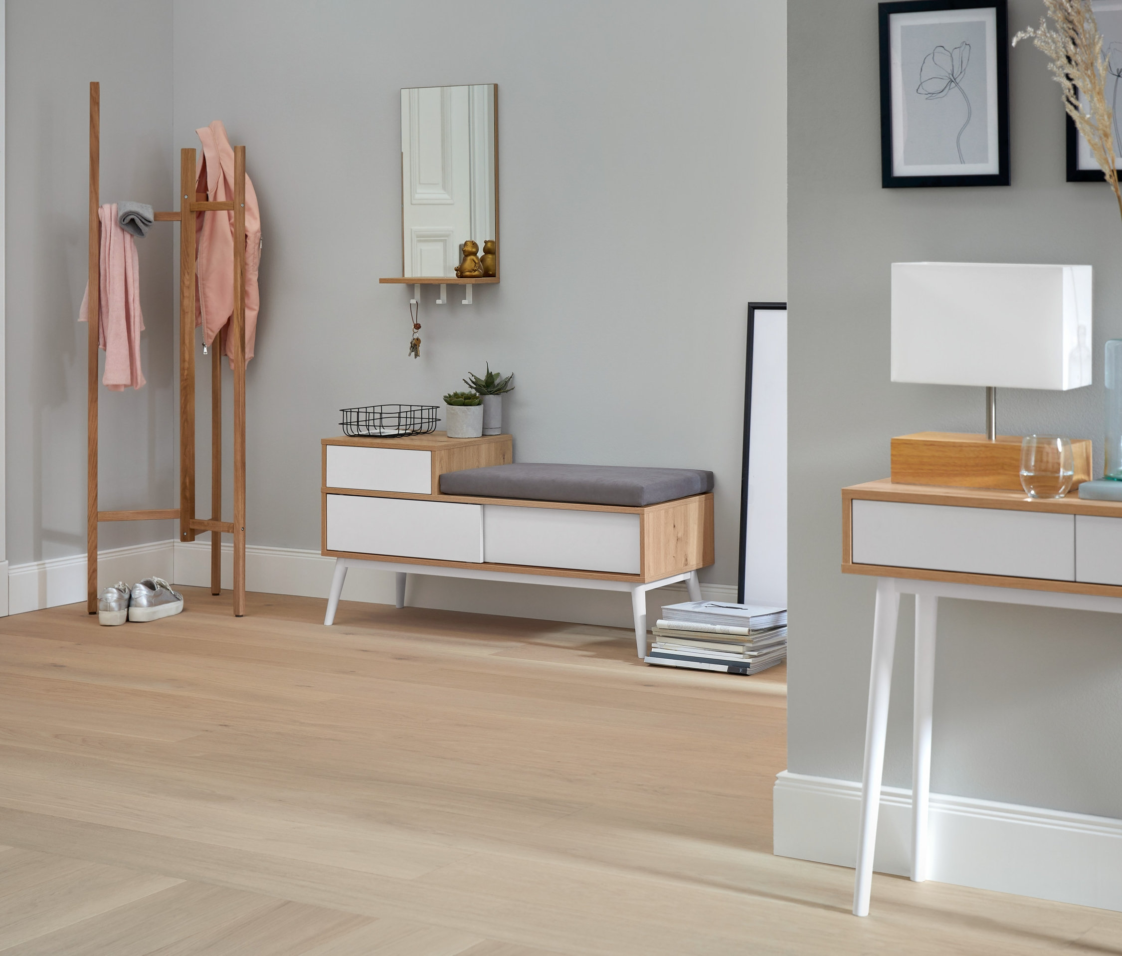 Eingangsbereich mit Sitzbank mit Schuhfach, Spiegel mit Ablage und Haken, Holzgarderobe und Tischleuchte mit Holzfuß.