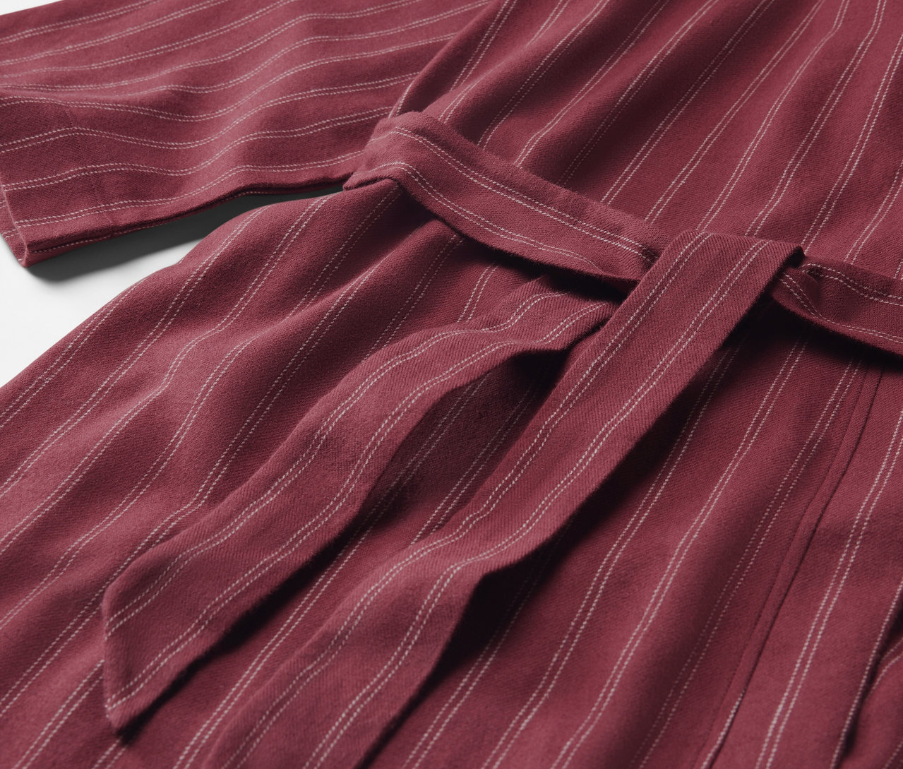 Detailaufnahme eines maroonfarbenen, gestreiften Bademantels mit gebundenem Gürtel.