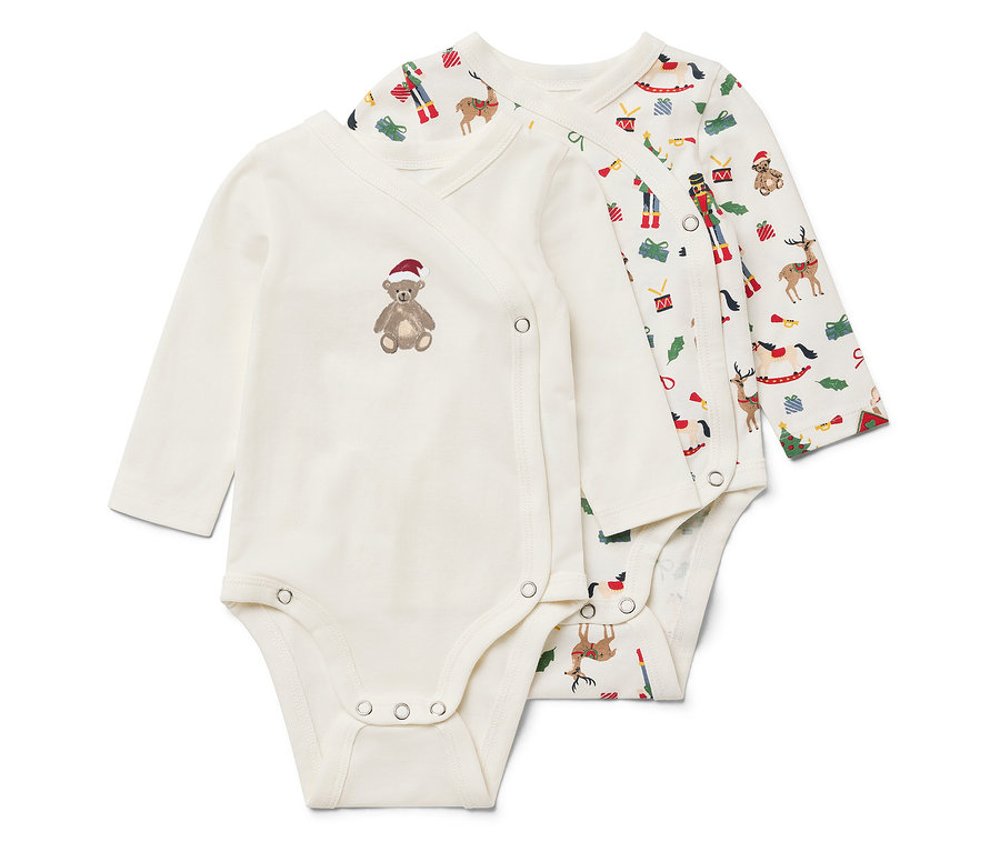 Zwei weiße Langarmbodys. Einer hat einen braunen Teddybären mit roter Mütze, der andere ein Weihnachtsmotiv.