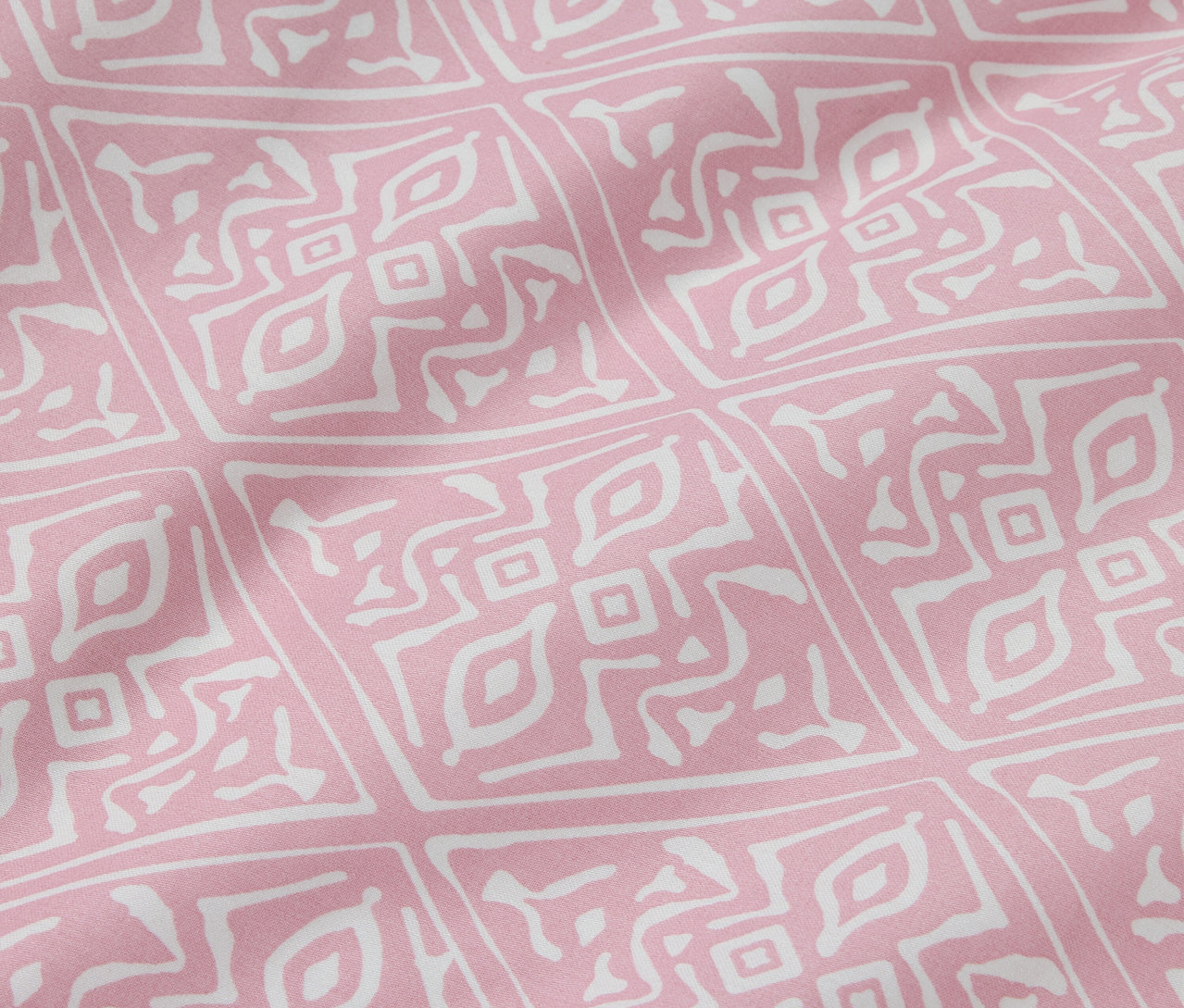 Nahaufnahme von normalgroßer Baumwollsatin-Bettwäsche mit geometrischem Muster in Rosa und Weiß.