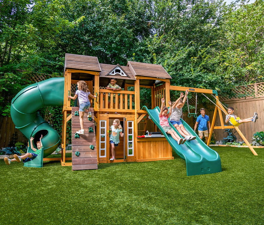 Mehrere Kinder spielen auf dem Spielturm »Bolzo« im Garten, klettern, rutschen und schaukeln.