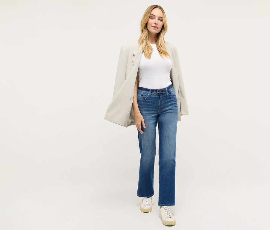 Frau trägt eine »Lara City« Straight Fit Jeans von Angels, ein weißes T-Shirt, einen Blazer und Turnschuhe.