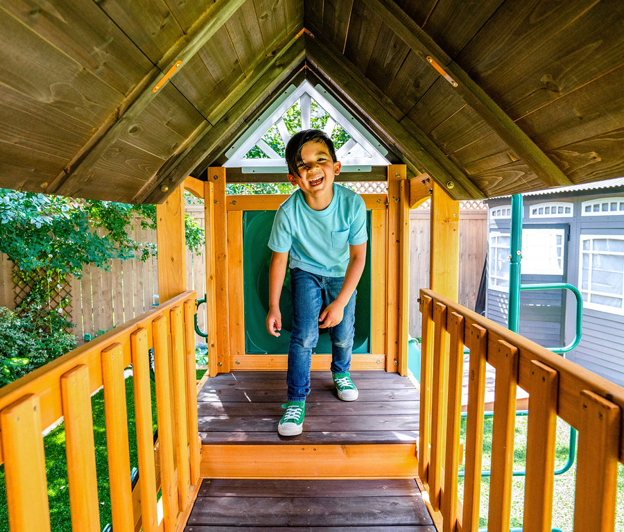 Lachender Junge steht im Spielturm »Bolzo«.