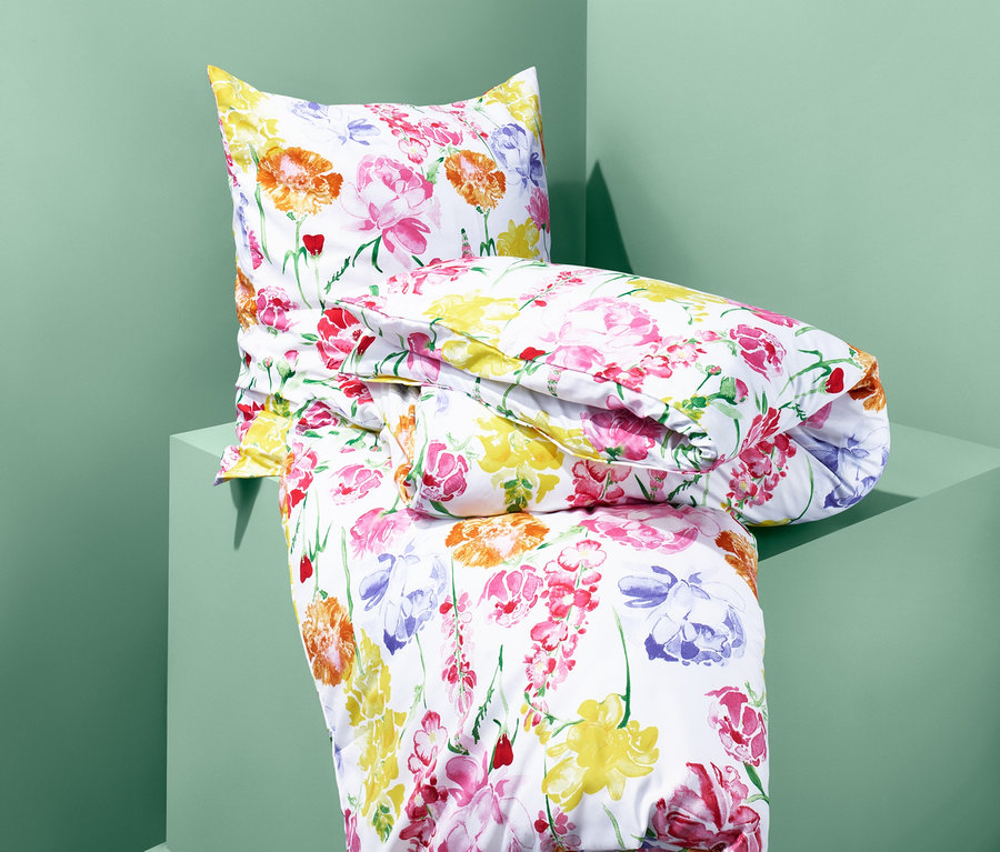 Auf einem grünen Podest liegt ein Set Microfaser-Bettwäsche mit Blumenmuster.