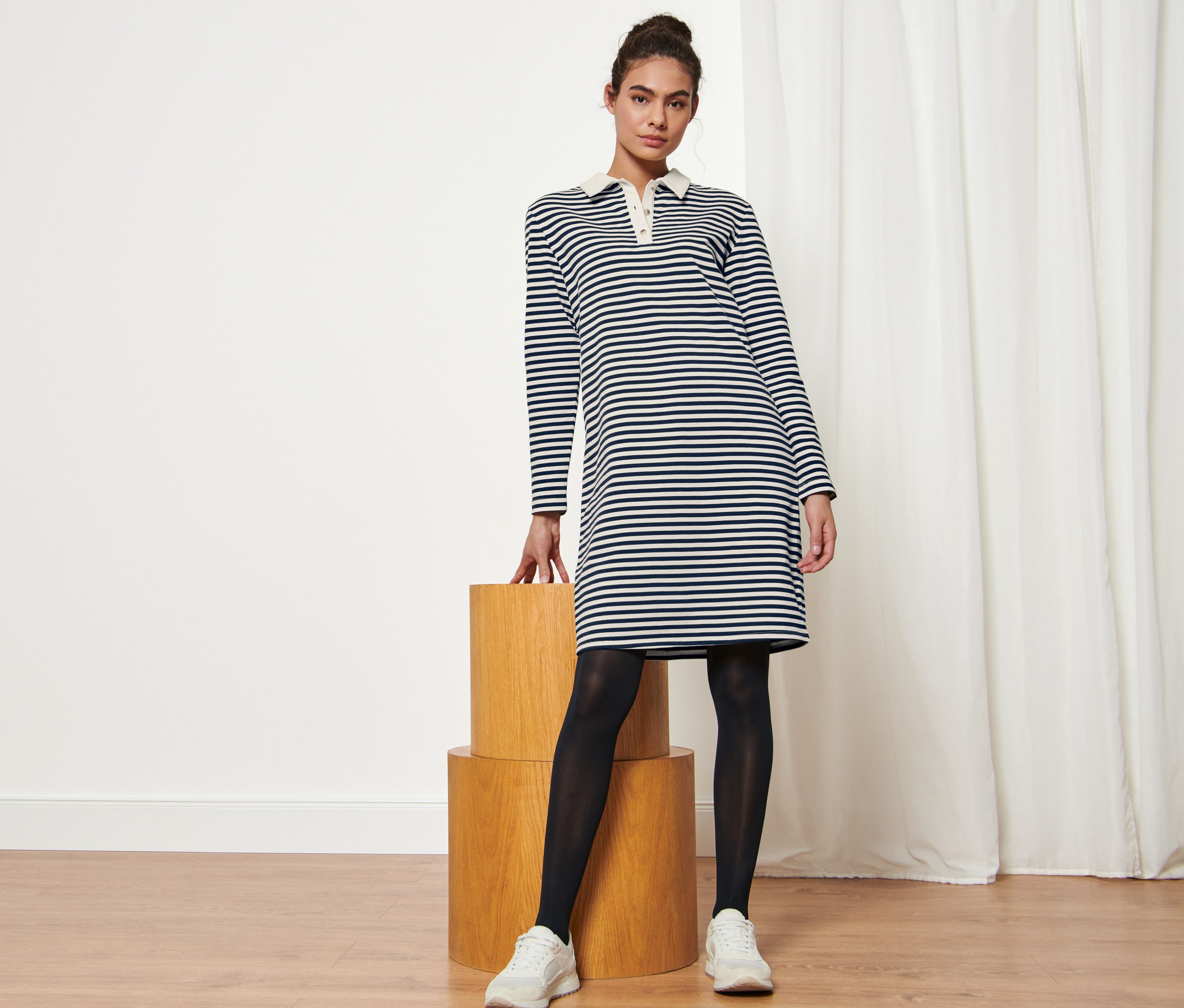 Frau posiert in gestreiftem Sweatkleid mit Polokragen.