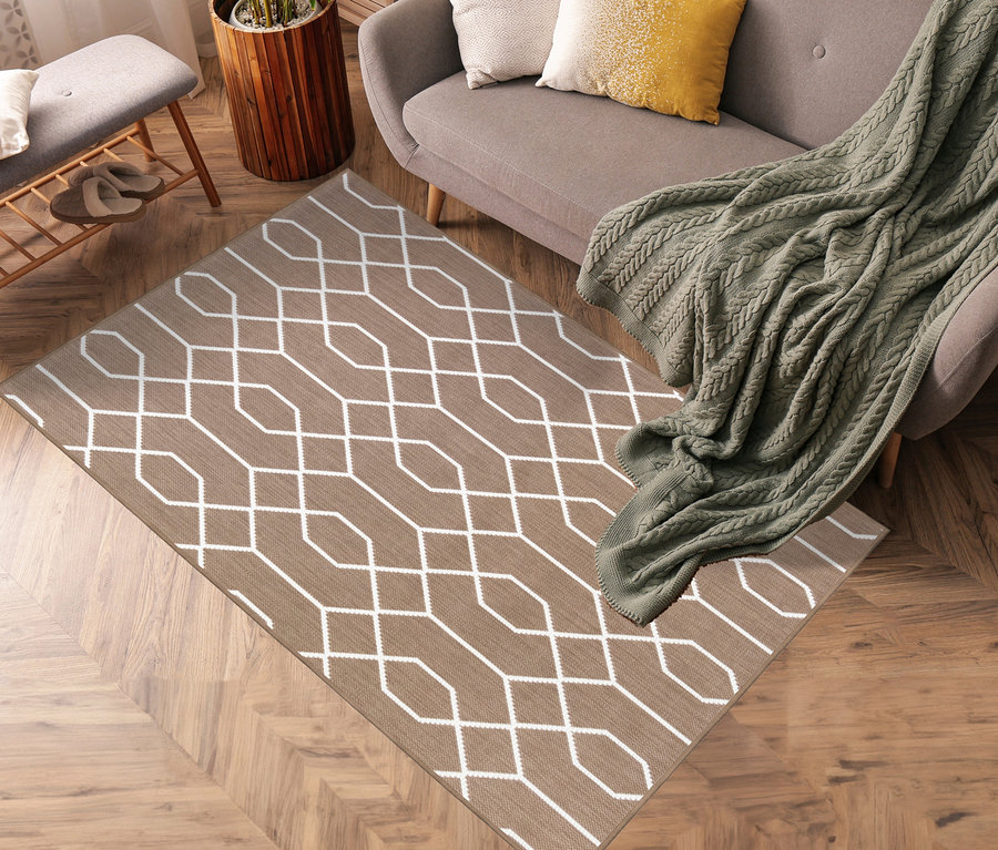 Brauner Teppich mit weißem geometrischem Muster liegt auf Holzboden neben grauem Sofa und Topfpflanze. Zu sehen sind Outdoor-Wendeteppiche »Geo River« in Braun, ca. 120 x 160 cm und ca. 160 x 220 cm.