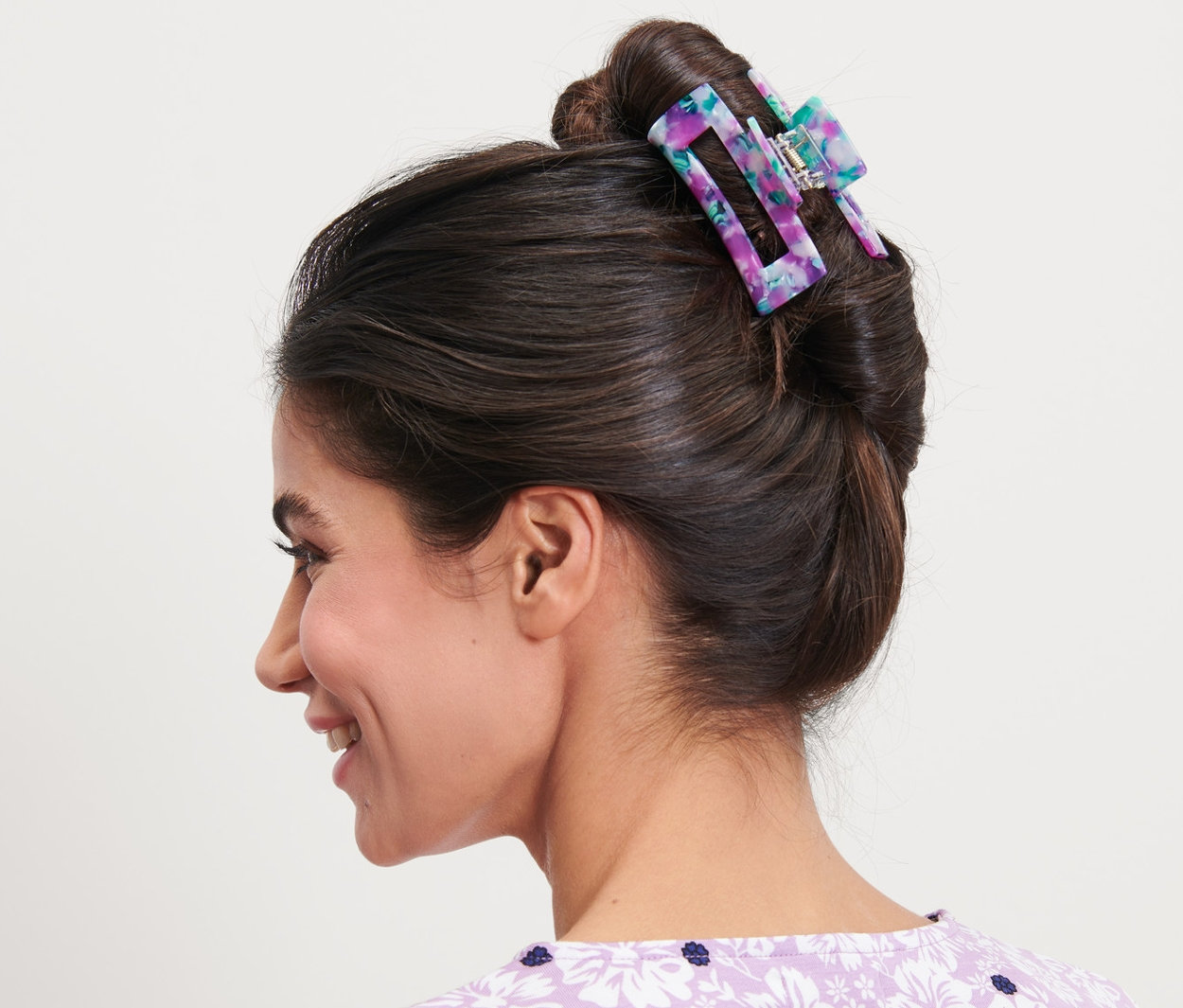 Profil einer lächelnden Frau mit einer blumigen Haarklemme im Haar.