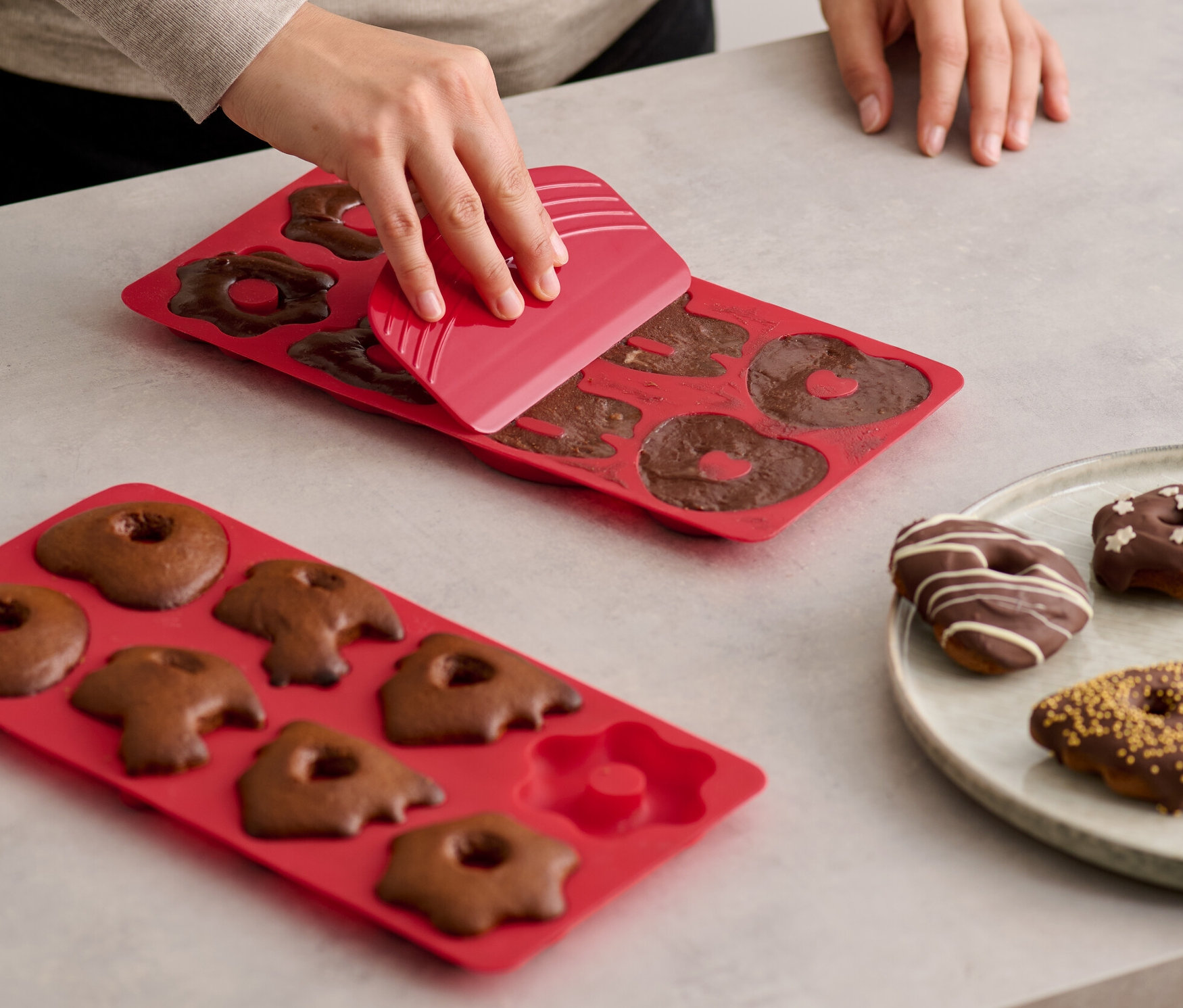 Eine Frau löst Lebkuchen aus einer roten 2 Mini-Lebkuchen-Backmatten.